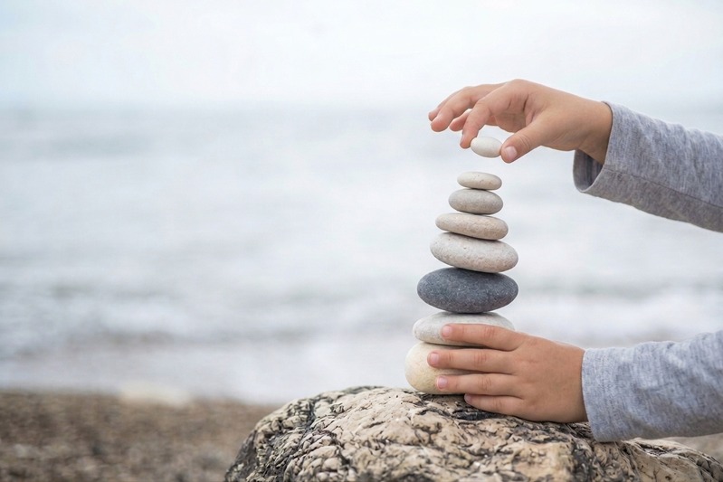 Mains déposant un galet sur une pile de pierres